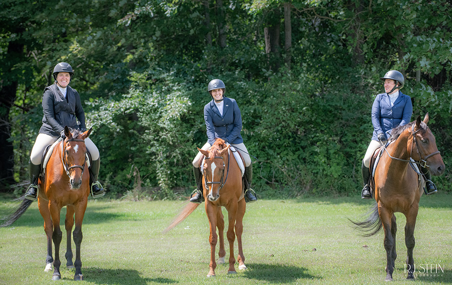 three riders on horses smiling