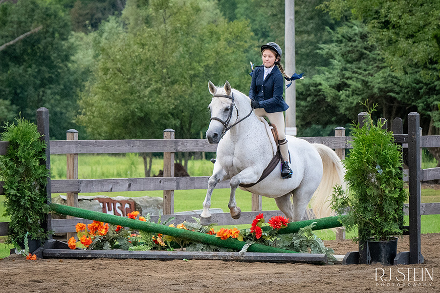 girl riding white horse jumping