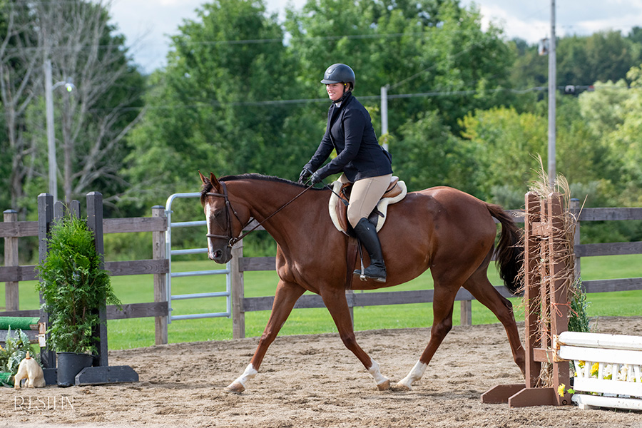 Women in black top riding a brown horse